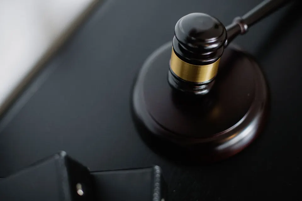 A wooden gavel with a brass band resting on a sound block