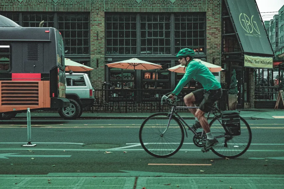 A cyclist in a helmet riding past a bus on a city street in the United States