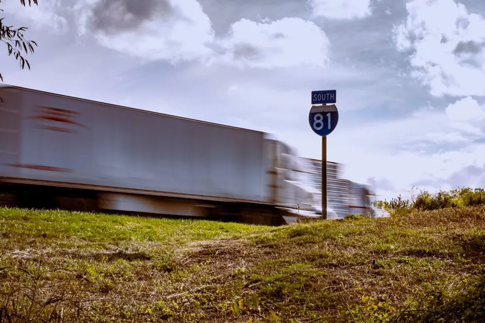 A tractor-trailer passing an Interstate 81 route sign