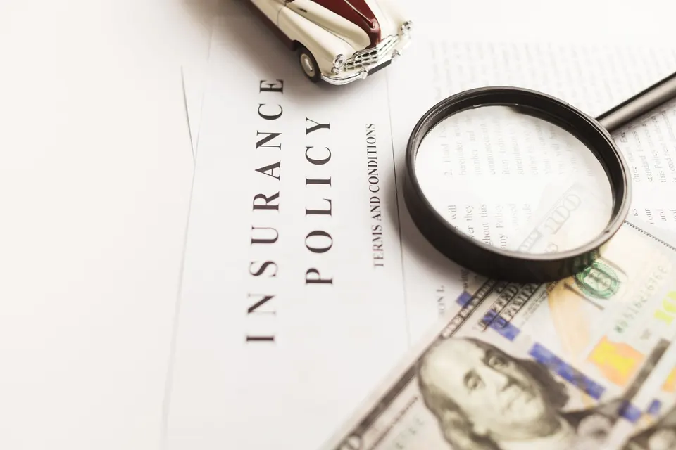 An insurance policy document with a magnifying glass and a toy car