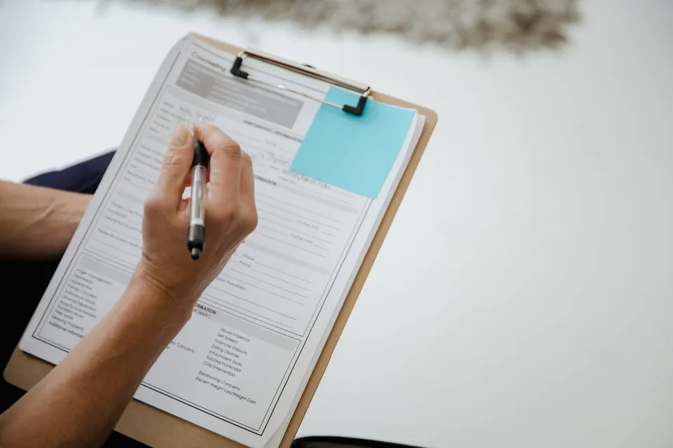A person filling in a report form on a clipboard