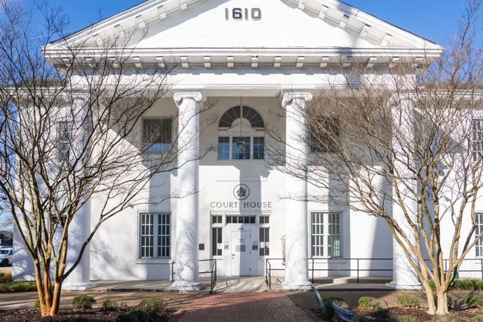 A white columned county courthouse with bare trees in front